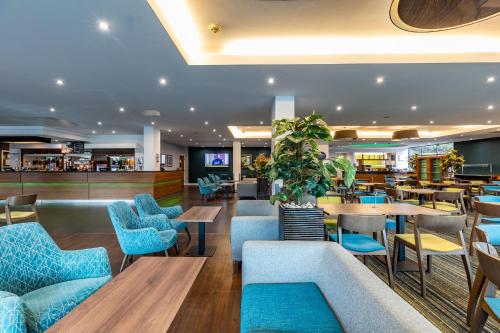 a restaurant with blue chairs and tables and a bar at Holiday Inn Express London Heathrow T5 by IHG in Slough