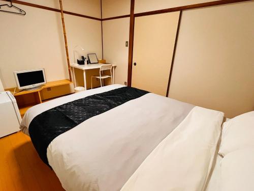 a bedroom with a large white bed and a desk at IKI Island HUB in Iki
