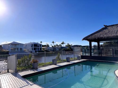 a swimming pool in front of a fence and some houses at Waterfront Haven Balinese Villa at Bundall in Gold Coast