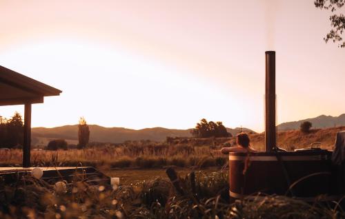 a person sitting in a tub in a field at Fiery Peak Eco-Retreat with Stargazing & Hot tub in Geraldine