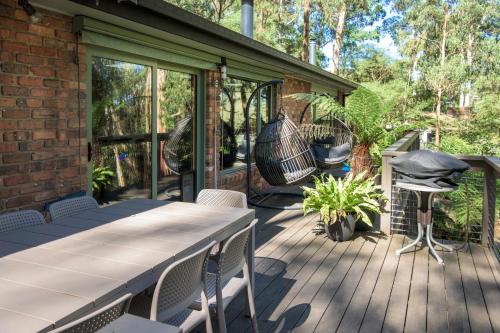 a patio with a table and chairs and a swing at Elliott Lodge - Getaway for the whole family/pets in Upwey