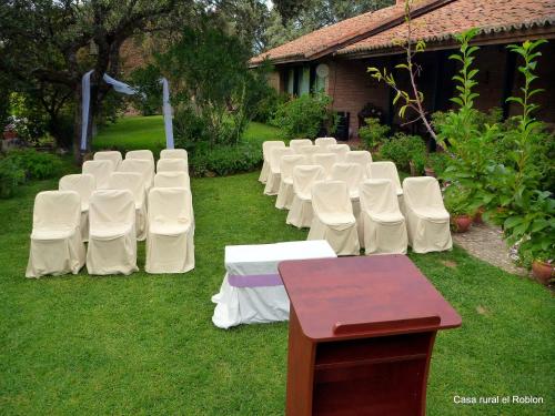 a row of white chairs sitting in the grass at Casa Rural El Roblon in Sartajada