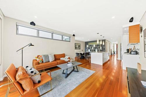 a living room with a couch and a table at Convenient 4BR with Private Pool close to Airport in Sydney