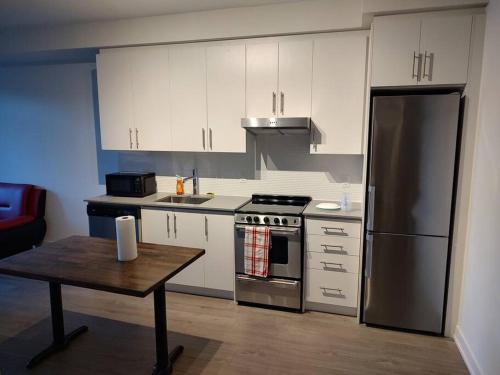 a kitchen with white cabinets and a stainless steel refrigerator at 1 Bedroom Suite - Brand New building, Double bed in Hamilton