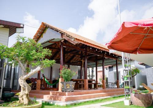 a house with a patio and an umbrella at Nguyễn Lagi Homestay in La Gi