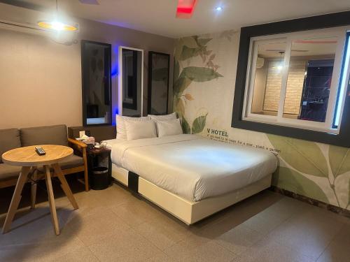 um pequeno quarto com uma cama e uma mesa em v motel em Busan