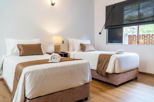 a bedroom with two beds and a television in it at Mulyo Hotel in Port Dickson