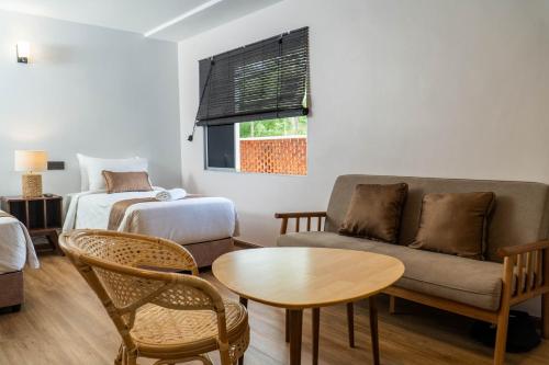 a living room with a couch and a table and a bed at Mulyo Hotel in Port Dickson