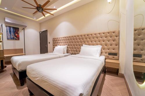 two beds in a hotel room with a headboard at Pink Mango A Boutique Hotel in Hisār