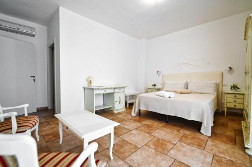 a white bedroom with a bed and a table at Olimpo B&B in Giurdignano