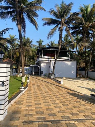 a building with palm trees in front of it at Rock n Ocean2 , Beach stay in Udupi