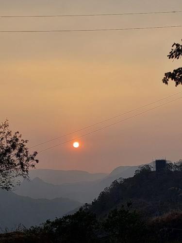 a sunset with the sun setting over the mountains at Karthika Homes in Anachal