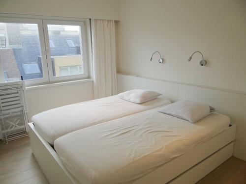 2 camas en una habitación blanca con ventana en Horizon 0501 located on the sea wall, en Nieuwpoort
