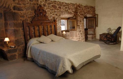 1 dormitorio con 1 cama grande y pared de piedra en La Premsa Hotel Rural en Cardona