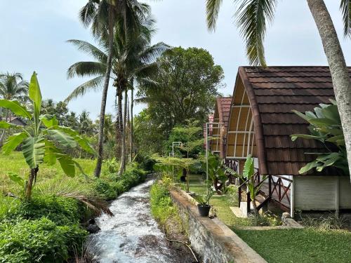 a stream next to a house and palm trees at Damuh Pertivi in Lovina