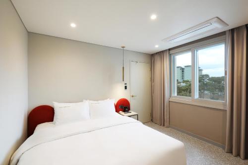 a bedroom with a large white bed and a window at Hotel The One in Gangneung