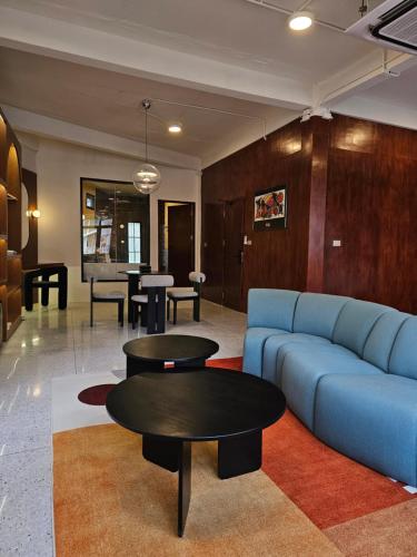 a living room with a blue couch and tables at Yaowarat Stay in Bangkok