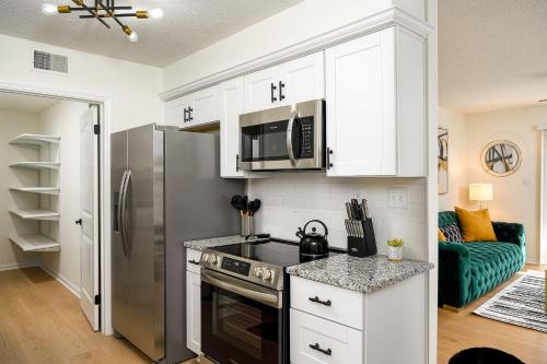 cocina con armarios blancos y nevera de acero inoxidable en Emerald Retreat - Central & Stylish - 2 BR/2 BA en Winston-Salem