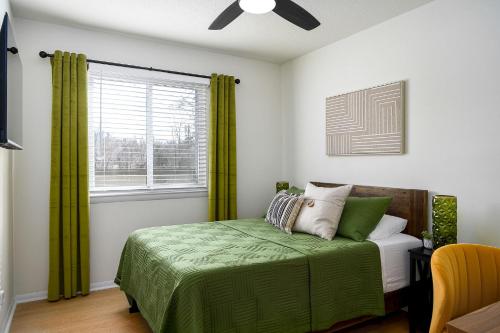 1 dormitorio con 1 cama con cortinas verdes y ventana en Emerald Retreat - Central & Stylish - 2 BR/2 BA en Winston-Salem