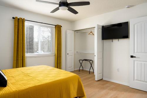 a bedroom with a yellow bed and a ceiling fan at Emerald Retreat - Central & Stylish - 2 BR/2 BA in Winston-Salem