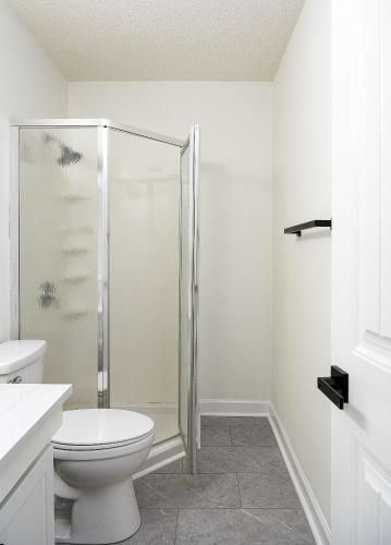 a bathroom with a toilet and a glass shower at Emerald Retreat - Central & Stylish - 2 BR/2 BA in Winston-Salem