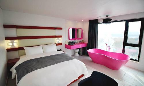 a bedroom with a large bed and a pink tub at Hapjeong Circle Hotel in Seoul