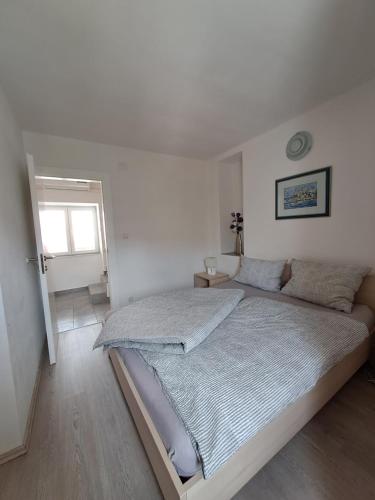 a white bedroom with a bed and a window at Greta in Vrbnik