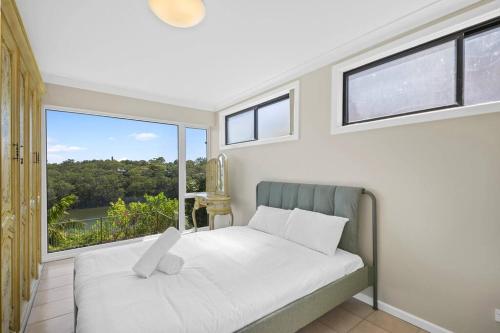 - une chambre avec un lit et une grande fenêtre dans l'établissement River View Oasis: Spacious 3-Bed House with Pool, à Sydney