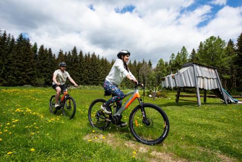 two people riding bikes in a grassy field at Penzion Sileo in Pribylina