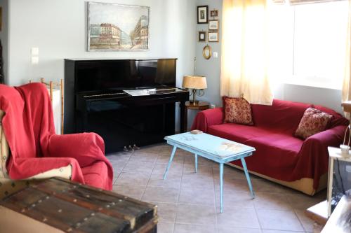 een woonkamer met een rode bank en een piano bij CHOPIN in Patra