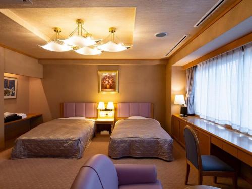 a hotel room with two beds and a desk at Hotel Symphony Sagae Onsen in Sagae