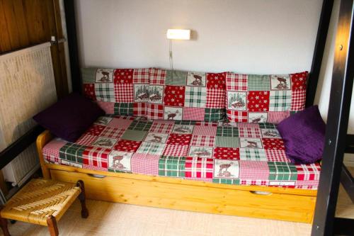 1 dormitorio con 1 cama con cuadros rojos y verdes en Résidence Le Bois D'aurouze - Studio pour 3 Personnes 244 en Saint-Étienne-en-Dévoluy
