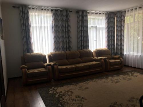 a living room with a couch in front of windows at Ай хаус in Cholpon-Ata