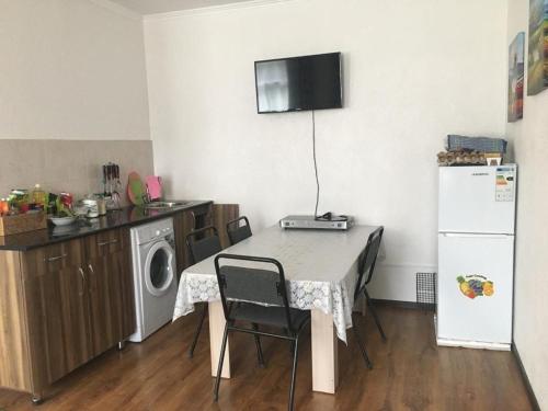 eine Küche mit einem Tisch mit Stühlen und einem Kühlschrank in der Unterkunft Ай хаус in Tscholponata