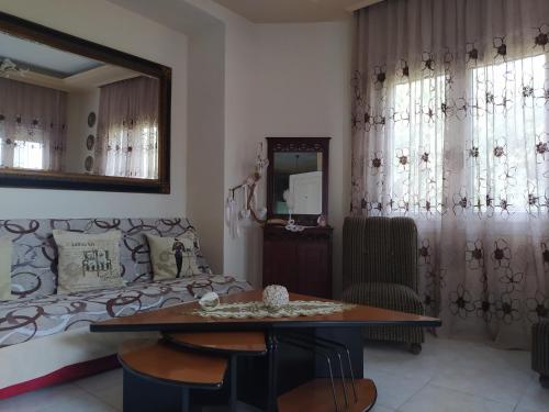 een woonkamer met een bank, een tafel en een spiegel bij SUN GARDEN in Skala Sotiros