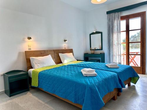 Un dormitorio con una cama azul con toallas. en Nostos Plaka Beach, en Plaka