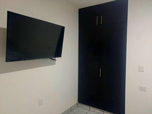 Elle comprend une armoire noire et une télévision murale à écran plat. dans l'établissement hogar, dulce hogar 1, à Torreón