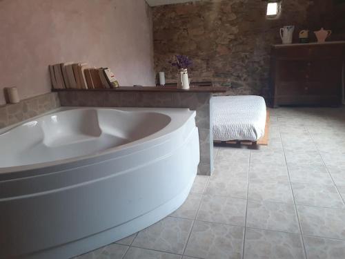 La grande salle de bains est pourvue d'une baignoire et de carrelage. dans l'établissement Maison de village atypique en bordure de forêt, à Corbère