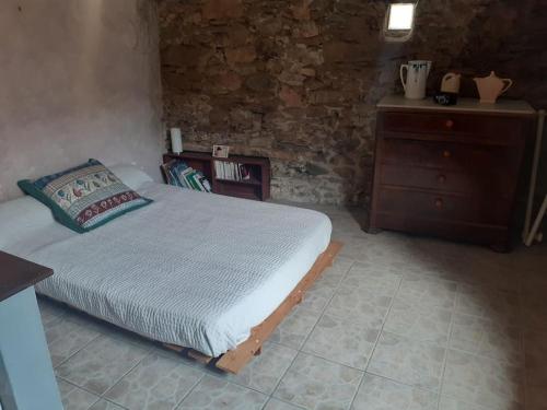 une chambre avec un lit et une commode en bois dans l'établissement Maison de village atypique en bordure de forêt, à Corbère