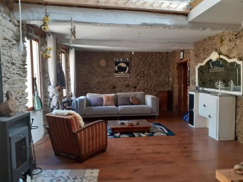 un salon avec un canapé et une table dans l'établissement Maison de village atypique en bordure de forêt, à Corbère