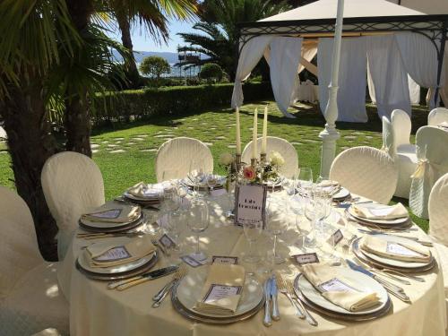 a table with white chairs and a table with glasses at Hotel Holiday Sul Lago in Bolsena