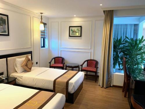 Habitación de hotel con 2 camas, mesa y sillas en Phong Nha Jasmine Hostel & Roof Top Bar en Phong Nha