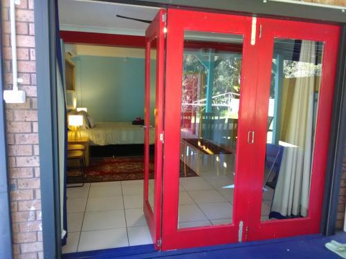 eine rote Tür, die in ein Zimmer mit einem Schlafzimmer führt in der Unterkunft 2 bedrooms 2 queen beds private bathroom own entry in Long Jetty