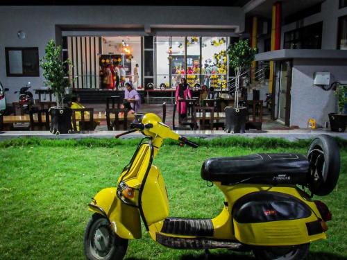 Un scooter amarillo estacionado en el césped de un patio. en Sangam Hotel, en Chirāwa