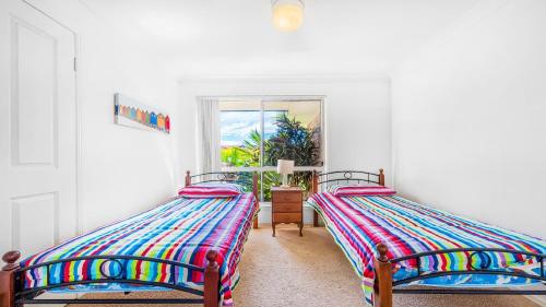 2 camas individuales en una habitación con ventana en Taine Court en Yamba