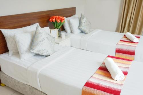 two beds in a hotel room with a vase of flowers at Simfoni Resort Langkawi by Perfect Host in Kuah