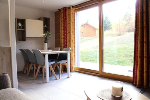 a living room with a table and chairs and a large window at Les Chalets Margot - Chalets pour 6 Personnes 651 in Le Dévoluy