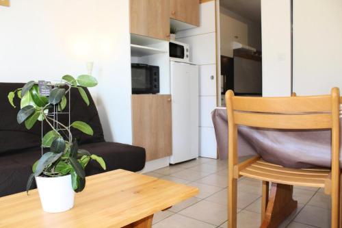 un salon avec une table, une chaise et une plante dans l'établissement Résidence Les Issarts - Appartement au pied des pistes de Superdévoluy MAE-9671, à Saint-Étienne-en-Dévoluy