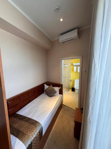 a small bedroom with a bed and a bathroom at H9 Hotel Nine Ulaanbaatar in Ulaanbaatar