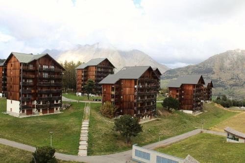 a group of apartment buildings with mountains in the background at Résidence Le Bois D'aurouze - Studio pour 4 Personnes 701 in Le Dévoluy